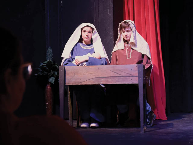 Two children dressed as Mary and Joseph in front of a manger on a stage
