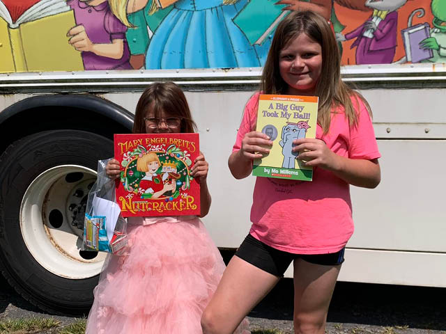 Two little girls with their book choices standing in front of the Bookmobile