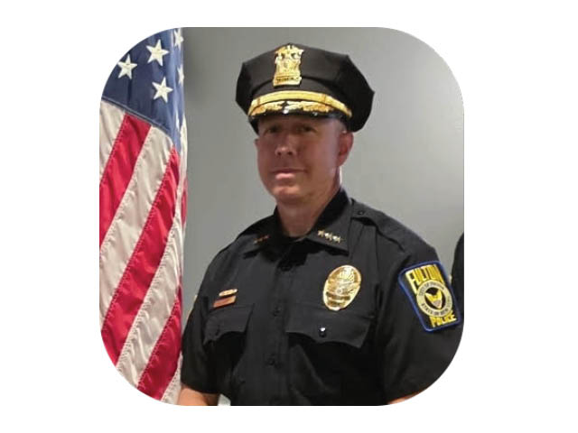 Fulton Police Chief Mike Curtis in police officer next to an American flag