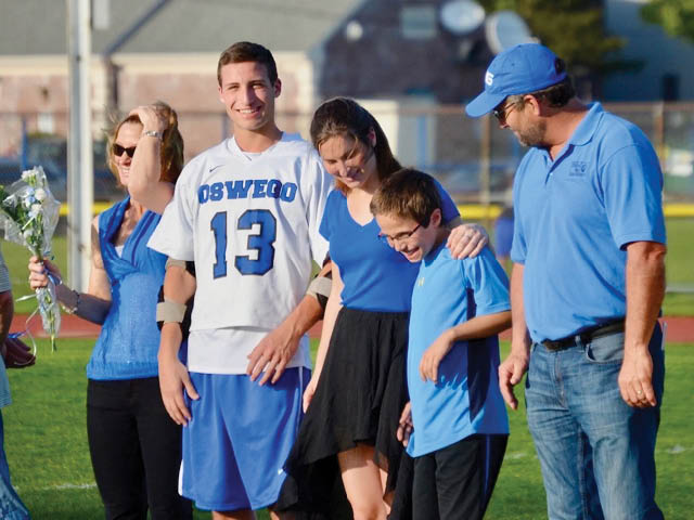 Garrett Dunsmoor (2nd from left) with members of his family on a school field wearing his Oswego 13 jersey