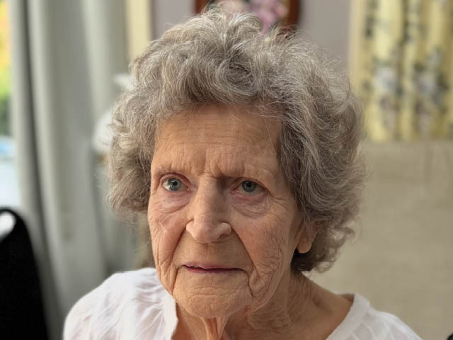 A white woman with short gray hair styled in a perm