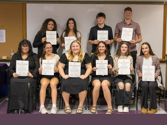 A photograph of 10 of the 12 new members of the National Honor Society from Hannibal: white students in two rows who are holding up certificates and smiling