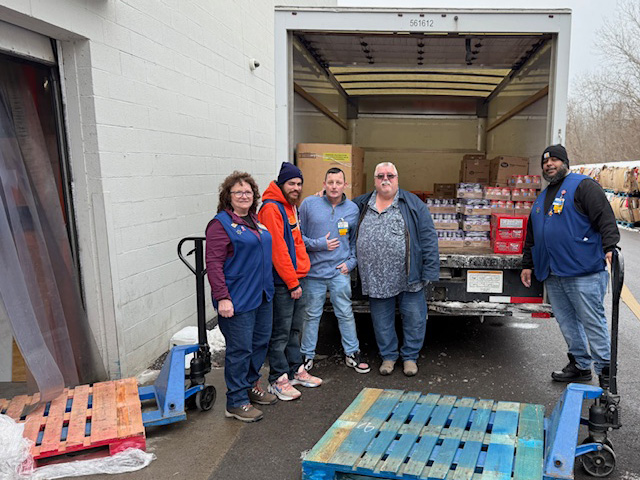 A small group of people including incoming Legislator Walker and a Walmart worker loading a box truck with food