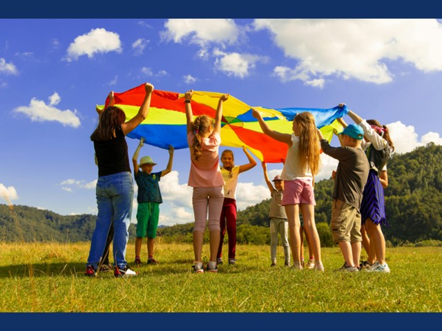 Photo of kids playing with a parachute in a field