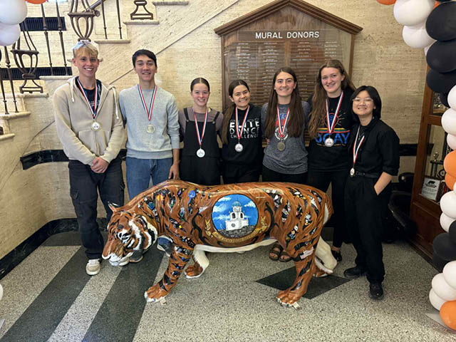 A group of high school students with medals in front of a small Mexico Tiger statue. 