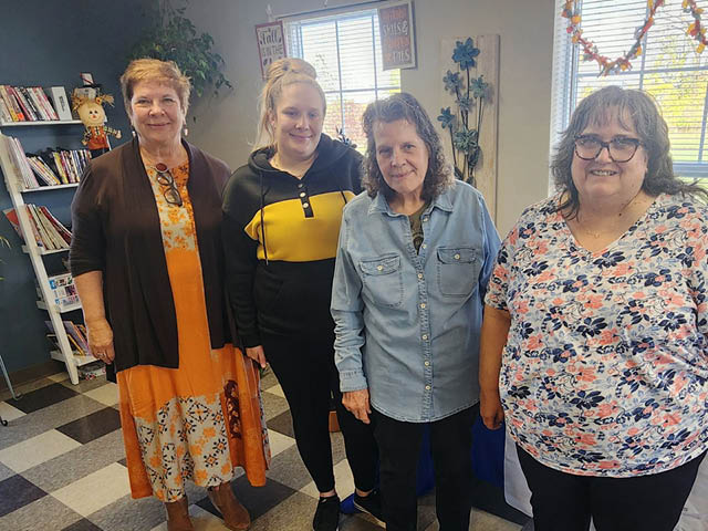 Four women standing in a row in a well-lit room