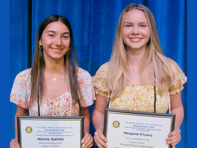 Two girls standing next to each other in front of a blue curtain