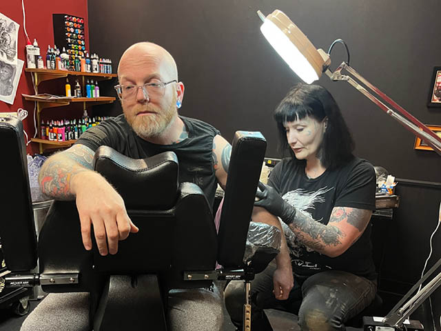 Penny Lane (right) tattoos a client in her shop