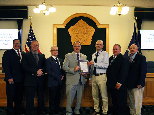 Men standing in the legislative chambers for Oswego County