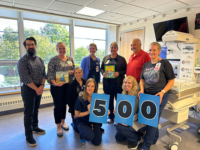 Imagination Library of Oswego County (ILOC) and Oswego Health celebrate registering over 500 children into the free book program through a community partnership via the Maternity Center. Top row L to R: ILOC Program Coordinator Andrew Eusebio, Oswego Health Maternity Center staff Michelle Rockwood, Zoe Kondravy, Allyson Becker, Dr Mahajan, Ryan Sincebaugh. Bottom row L to R: Pam Mayer, Sam Doud, and Sarah Tyner, NNP.