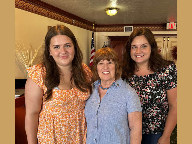 The exchange student stands next to two Rotarians