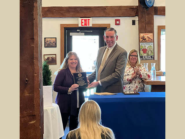 Sheila Dion receiving award from Patrick Dewine in the club house at Kristen's Kitchen