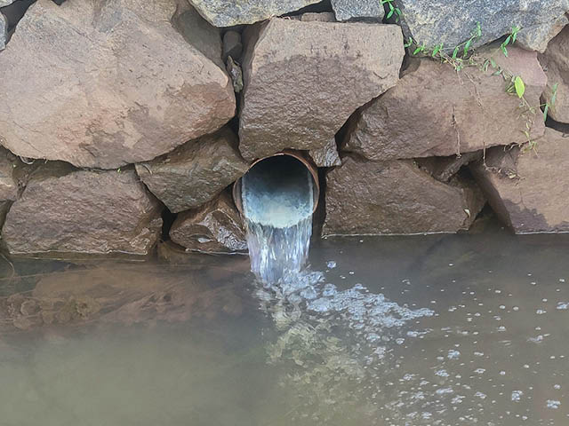 Drain emptying clear water into a pond