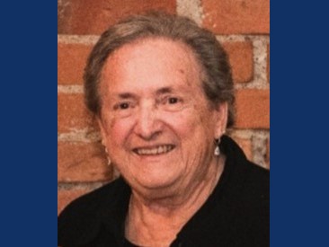 woman in short brownish hair smiling with dangly earings in a black shirt
