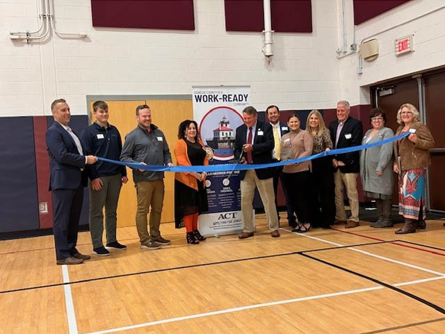A group of people at a ribbon cutting in a school gym