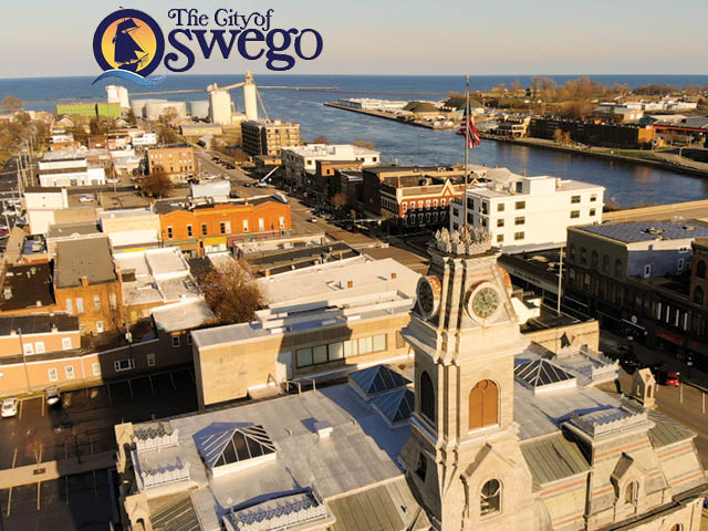 Drone photo of Civic Plaza with the river and lake in the background; City of Oswego logo overlaid at the top of the photo