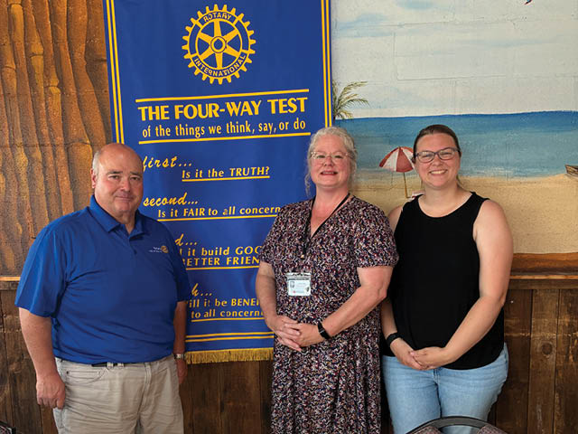 Brian Pulvino, Virginia Bough, and Bekkah Frisch posing in front of the Rotary Banner