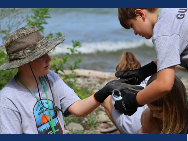 Two boys with black gloves and two girls in background on shore of the lake