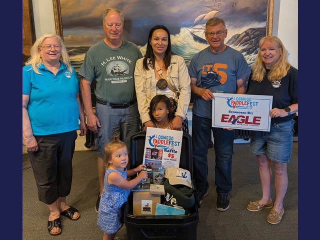 Group photo of the winner and her family with the raffle package alongside HLWMM staff and board members