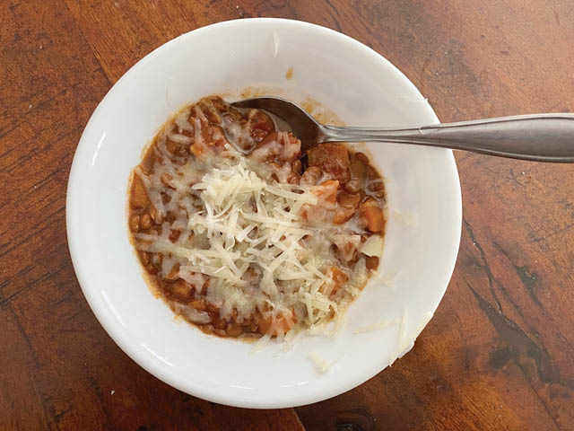 Lentil stew in a white bowl, topped with cheese