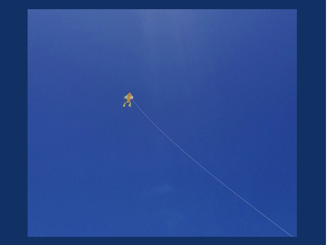 One small kite with very long lead in a deep blue sky