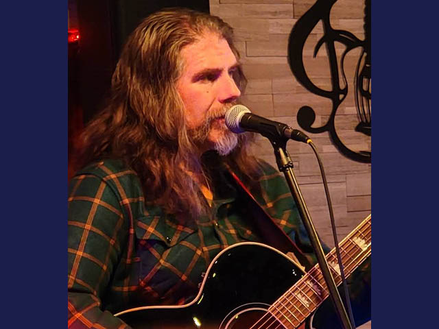 Photo of Lloyd Polak singing and playing guitar