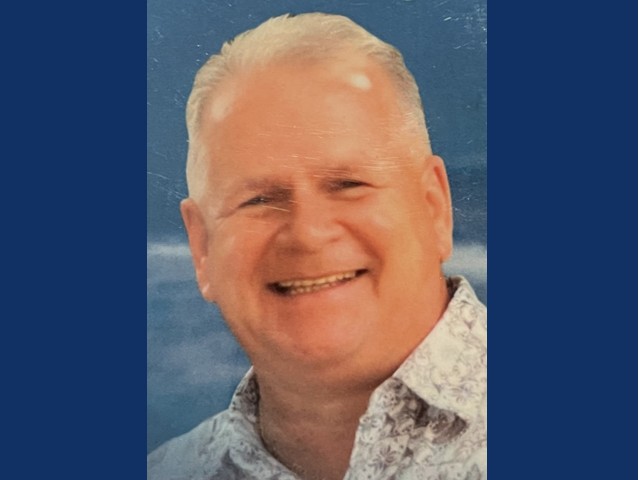 older man with short gray hair smiling in collared shirt