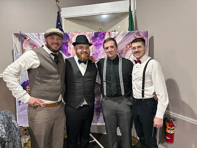 A group of men at a previous murder mystery dinner dressed in a '20s style