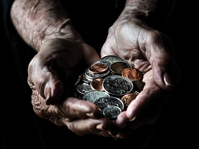 Photo of an older man holding silver and bronze coins, including pennies and quarters