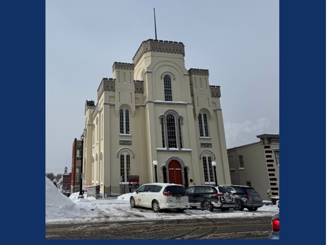 Large three floor brick building with rod on top surrounded by snow.