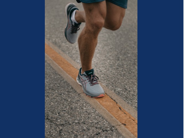 Legs running on yellow road line with gray sneakers  