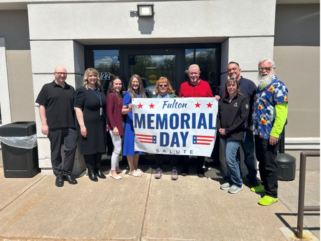 Several people standing with Memorial Day Salute Banner between them