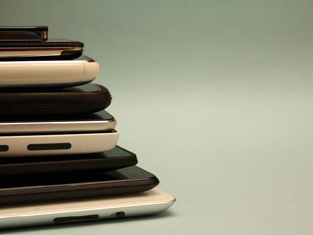 A stack of electronic devices, including phones and tablets