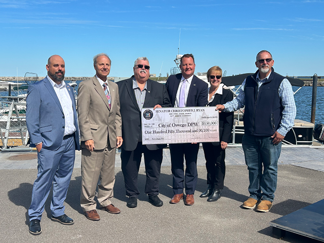 Group photo of Oswego officials with Sen. Ryan and a presentation check at Wright's Landing