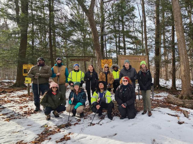 A group of volunteers in the woods on a snowy hill