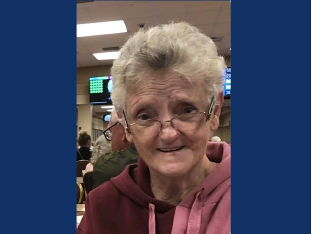 Senior woman with short gray hair, wire glasses and mauve colored hoodie