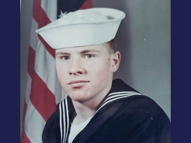 Favata as a young man in a sailor's uniform with the US flag in the background