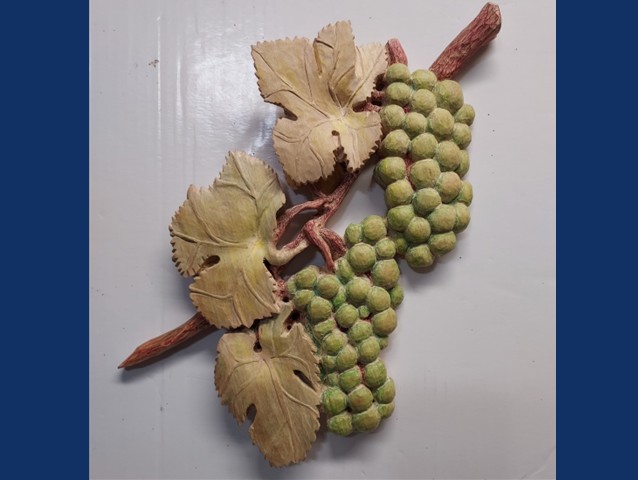 green grapes with light brown  leaves hanging from a grape vine branch.