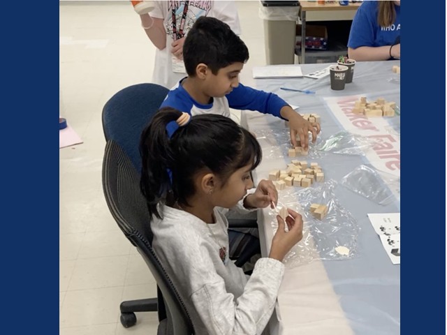 a young boy and girl sitting at a table with wooden plain blocks and directions