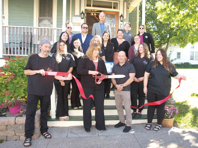 People standing on stairs around Tonia Reed, who is cutting a red ribbon